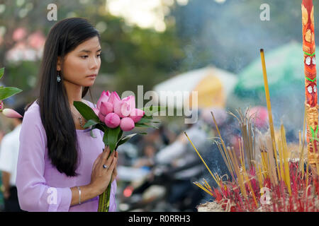 Femme en prière bouddhiste vietnamien à temple holding bouquet bourgeon fleur de lotus Banque D'Images