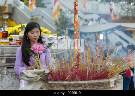 Femme asiatique bouddhiste priant dans le temple, des boutons de fleurs de lotus holding bunch, Vietnam Banque D'Images