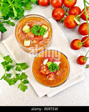 Soupe de tomate gaspacho dans deux verres avec le persil et les légumes sur une serviette dans le contexte de la table en pierre haut Banque D'Images