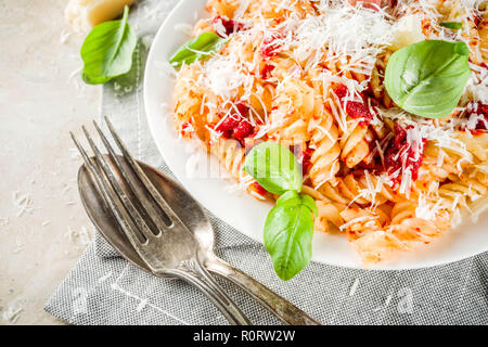 La cuisine italienne, les pâtes fusilli avec sauce tomate, parmesan râpé et de basilic, de la lumière table de pierre copie espace Vue de dessus Banque D'Images