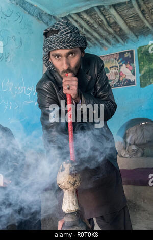 Homme qui fume du haschich avec un bong près de la tombe d'un saint soufi, ancienne Balkh, au nord de l'Afghanistan Banque D'Images