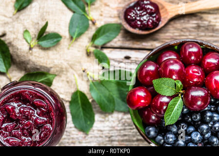 Pot rustique avec confiture de cerises aigres et cerises fraîches dans un bol, vue de dessus Banque D'Images