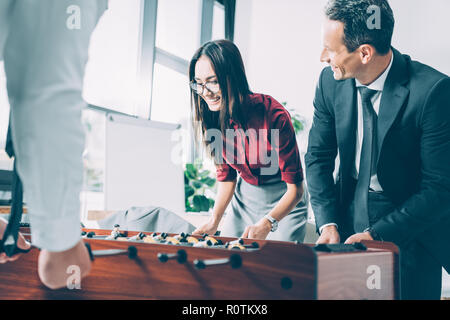 Heureux d'affaires multiraciale playing table football in modern office Banque D'Images