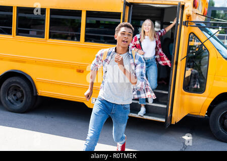 Les élèves adolescents multiethnique couple court de school bus Banque D'Images