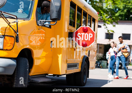 Senior school bus driver à l'adolescence à marcher derrière le bus Banque D'Images