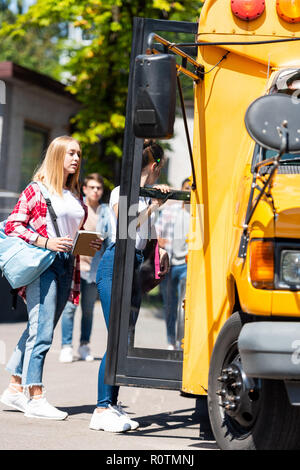 Vue latérale du groupe de spécialistes de l'adolescence bus entrant à l'école après les cours Banque D'Images