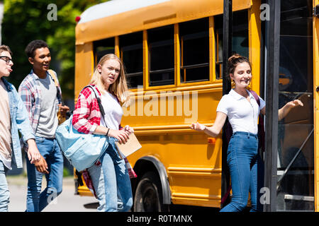 Groupe d'étudiants qui entrent dans l'adolescence après les leçons d'autobus scolaires Banque D'Images