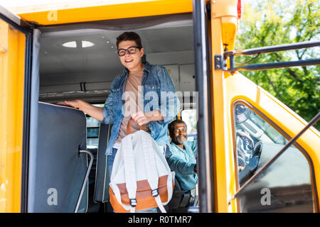 Happy teen écolier sortant de school bus driver tout en le regardant Banque D'Images