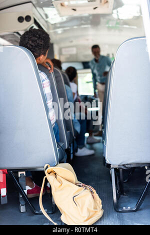 Vue arrière de l'adolescent students sitting at school bus et d'écoute à l'enseignant Banque D'Images