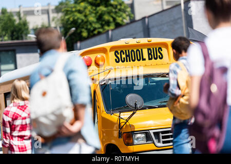 Vue arrière du groupe de spécialistes de l'adolescence avec des sacs à dos à l'école à pied bus après l'école Banque D'Images