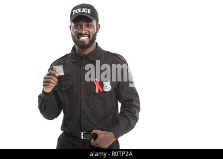 Smiling african american agent de police avec la sensibilisation au sida ruban rouge holding condom isolated on white Banque D'Images