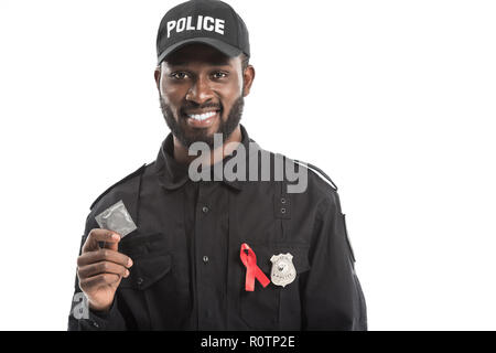 Happy african american agent de police avec la sensibilisation au sida ruban rouge holding condom isolated on white Banque D'Images