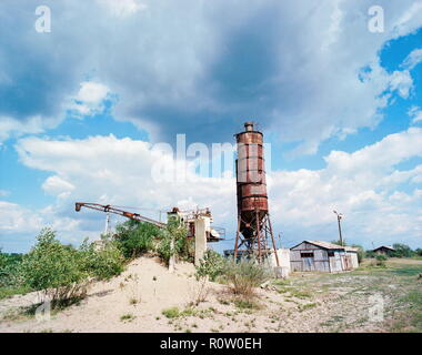 Ancienne silo et machine industrielle, bâtiment, sable, nuages, ciel bleu Banque D'Images