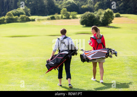 Vue arrière du couple walking on golf golf green Banque D'Images