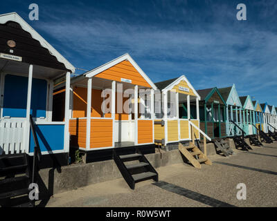 Une rangée de cabines de plage aux couleurs vives le long du front de mer à Southwold contre un ciel bleu Banque D'Images
