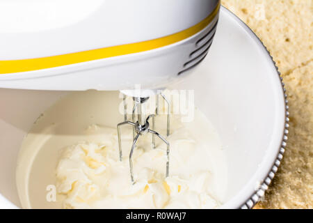 Le mélange d'un mélange de crème pour une pâte à gâteau dans un bol avec le mélangeur électrique Banque D'Images