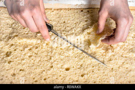 Gâteau éponge coupe sur couches. La préparation d'un gâteau tarte, le détail des mains et couteau, close-up Banque D'Images