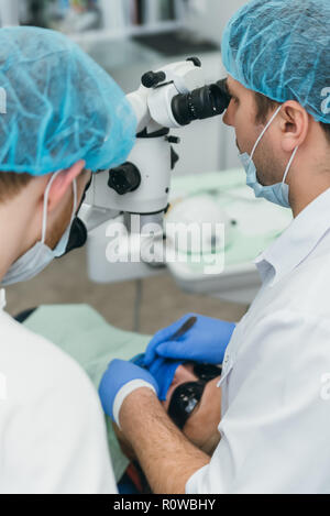 Médecin utilisé microscope. Dentiste est de traiter le patient en cabinet dentaire moderne. L'opération est réalisée à l'aide de batardeau. Client est inséré et dents restaurées, faire remise. Banque D'Images