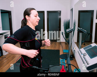 Femme en costume de stimulation musculaire training Banque D'Images