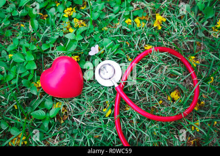 Concept de soins de santé. Stéthoscope rouge avec cœur rouge sur fond d'herbe verte. Banque D'Images