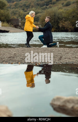 L'homme propose de femme près de river Banque D'Images