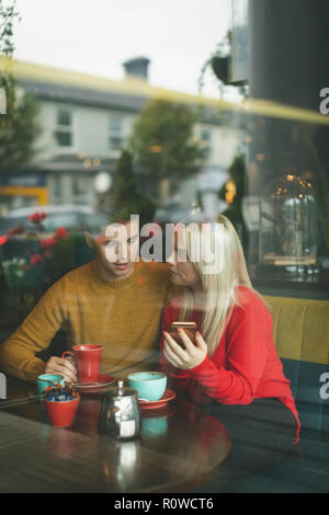 Couple discussing on mobile phone in cafe Banque D'Images