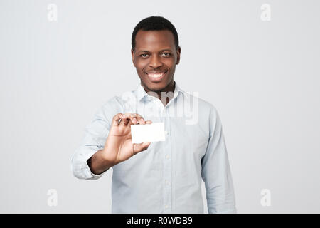 Young African man holding bank carte de visite sur fond gris Banque D'Images