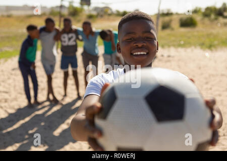 Boy holding football dans le sol Banque D'Images