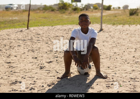 Garçon assis sur le football dans le sol Banque D'Images