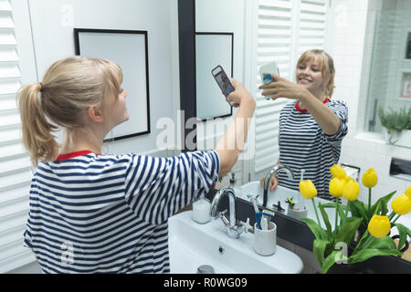 Woman on mobile phone selfies dans salle de bains Banque D'Images