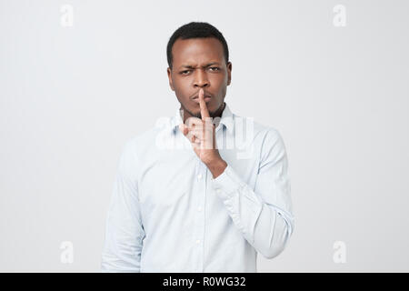 African Male maintient l'index sur les lèvres, lui demande de ne pas faire connaître son secret à d'autres personnes. Banque D'Images