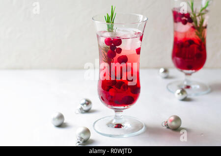 Cocktail aux canneberges avec de la glace et de romarin sur fond blanc, verre Banque D'Images