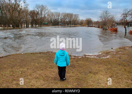 L'observation de l'enfant dans l'inondation de la rivière ville après la fonte des neiges au printemps. Catastrophe naturelle. L'inondation de la rivière au printemps lors de la fonte de la neige. Les crues du printemps Banque D'Images