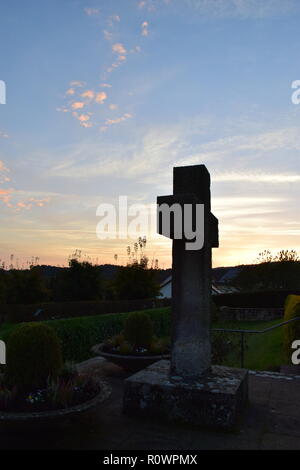 Chronologie de la soirée ciel crépuscule vu de derrière une croix en pierre de sable sculpture au cours de la coucher du soleil soleil dans le cimetière civil Reimsbach, Centre, Banque D'Images