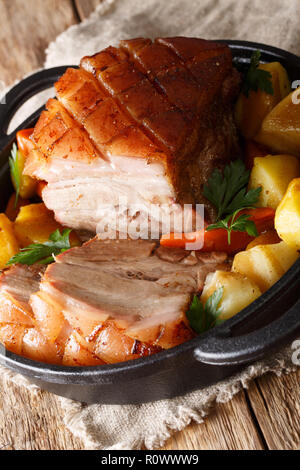 Krustenbraten Rôti de porc avec couenne croustillante avec légumes close-up dans une poêle sur la table. La verticale Banque D'Images