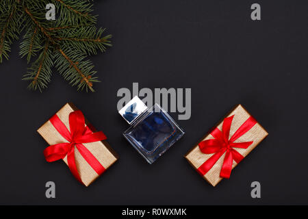 Décoration de Noël. Des boîtes-cadeaux, flacon de parfum et naturel sapin branche sur fond noir. Vue d'en haut. Carte de vœux de Noël concept. Banque D'Images