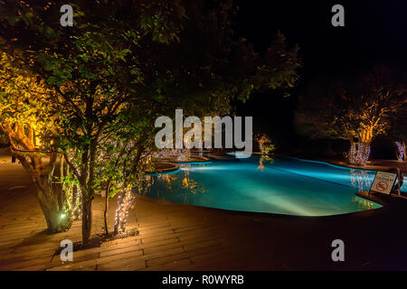 Piscine ouverte avec des arbres autour d'elle en soirée Banque D'Images