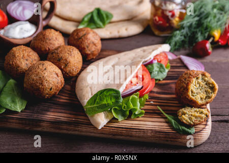 Falafel, légumes frais, la sauce et le pain pita sur table en bois Banque D'Images