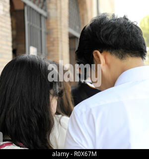 Young Asian couple regardant le smartphone parmi le peuple. Rome, Italie Banque D'Images