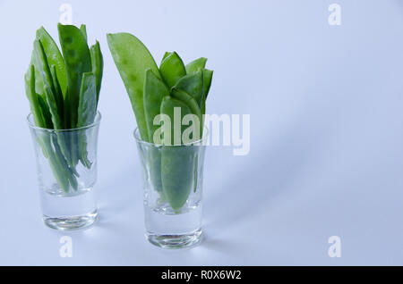 Un tas de pois mange-debout dans un verre sur fond blanc Banque D'Images