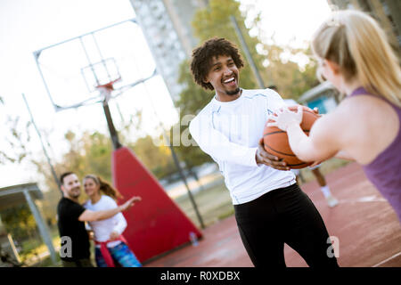 Couple multiracial jouant au basket-ball sur une cour au jour outumn Banque D'Images