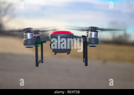 Petit rouge et gris drone avec joint d'atterrissage et batterie à demi-charge battant contre l'arrière-plan flou Banque D'Images