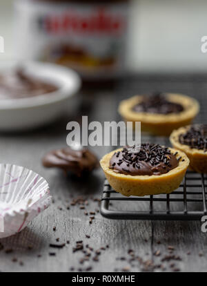 Tartelettes nutella avec des vermicelles de chocolat sur un support avec du Nutella en rack à l'arrière-plan Banque D'Images