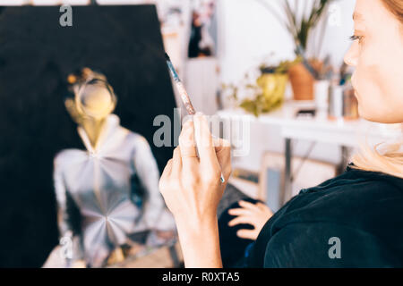 Gros plan d'une artiste peintre féminin tout en maintenant un pinceau Banque D'Images