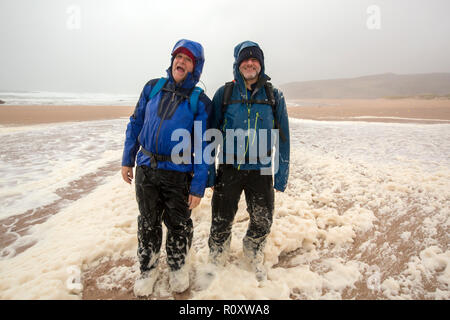 Les randonneurs de spume ou écume de mer d'être soufflé le long de la plage de Sandwood Bay lors de coups de vent, Sutherland, Scotland, UK. Banque D'Images