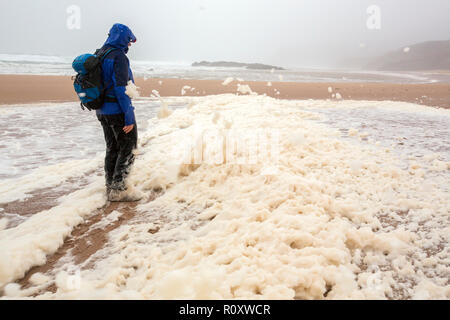 Les randonneurs de spume ou écume de mer d'être soufflé le long de la plage de Sandwood Bay lors de coups de vent, Sutherland, Scotland, UK. Banque D'Images