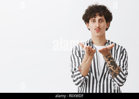 L'envoi de mes baisers passionnés de fans. Portrait of romantique et beau jeune homme avec moustache et cheveux bouclés sombres en chemise rayée envoi mwah étant dans l'amour avec propre reflet Banque D'Images