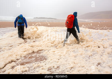 Les randonneurs de spume ou écume de mer d'être soufflé le long de la plage de Sandwood Bay lors de coups de vent, Sutherland, Scotland, UK. Banque D'Images