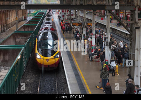 Un pedolino Virgin Trains train arrivant en gare de Preston humide le long d'une plate-forme bondé Banque D'Images