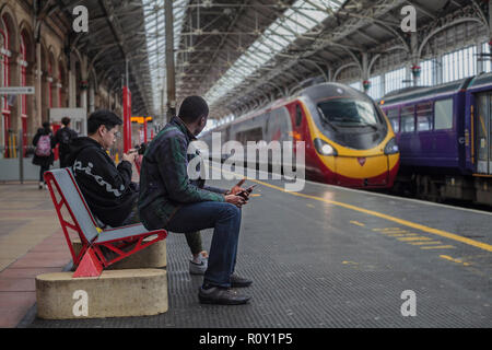 Un Virgin Trains pendolino arrive à Preston sur la ligne principale de la côte ouest avec les passagers en attente. Banque D'Images